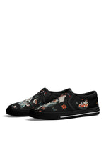 Angled front view of black frog tattoo slip-ons showing mushroom and butterfly illustrations