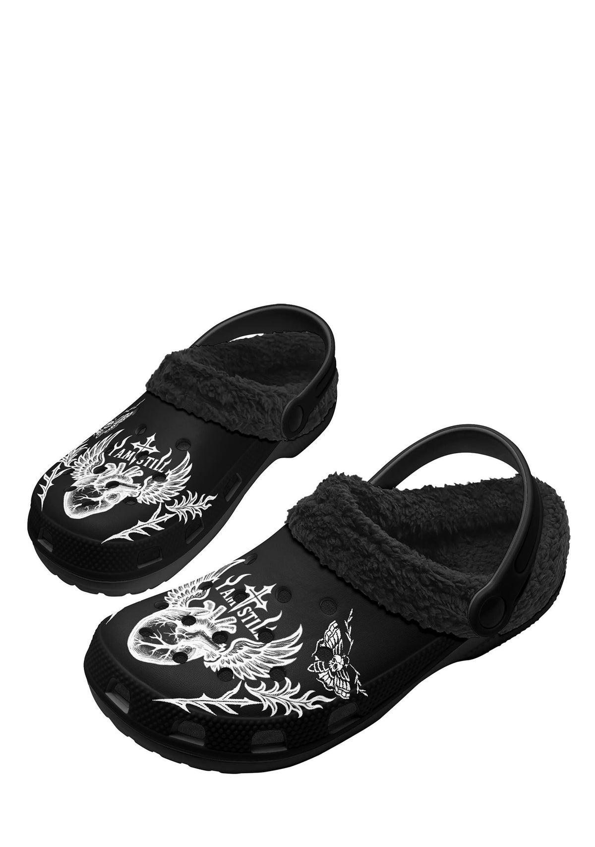 Top-down flat lay of both slippers side by side, revealing the full winged heart design with the gothic cross and "I Am Still" text on each black slipper